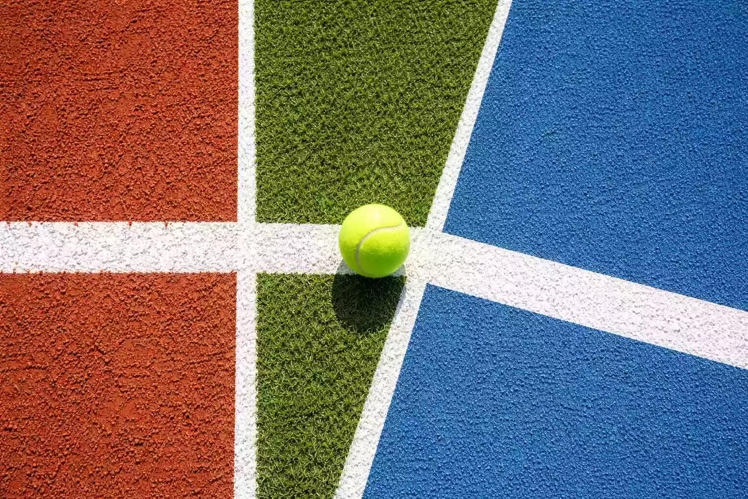 Drei verschiedene Tennisbeläge nebeneinander: Sandplatz, Rasen und Hartplatz