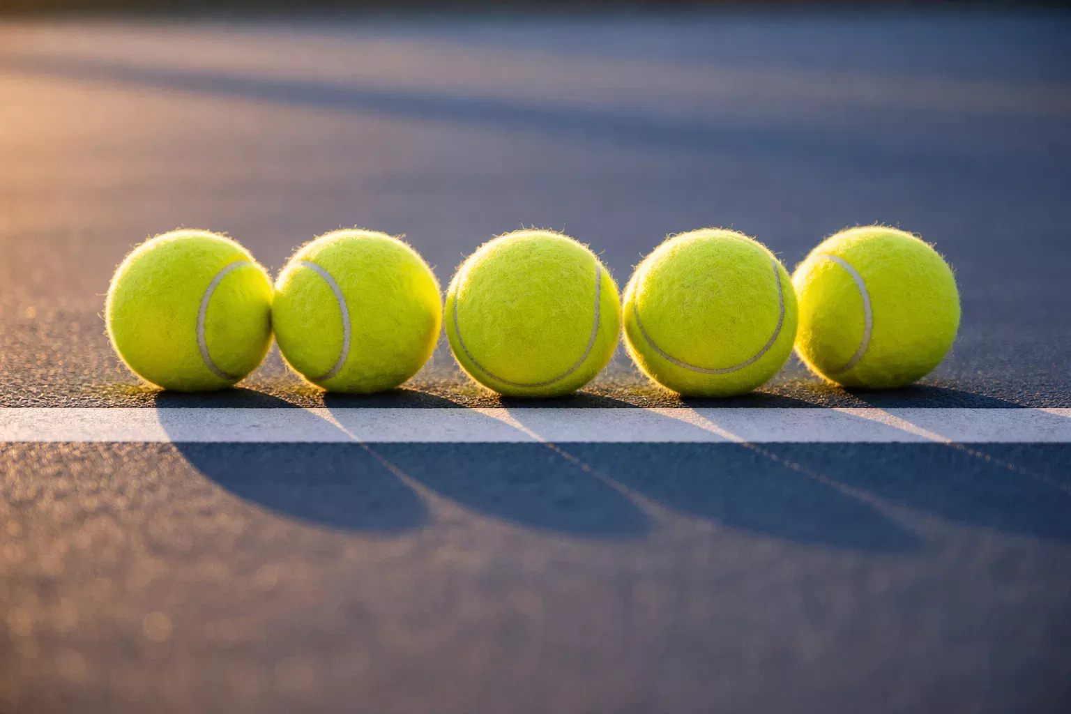 Mehrere Tennisbälle auf einer Reihe auf einem Tennisplatz angeordnet