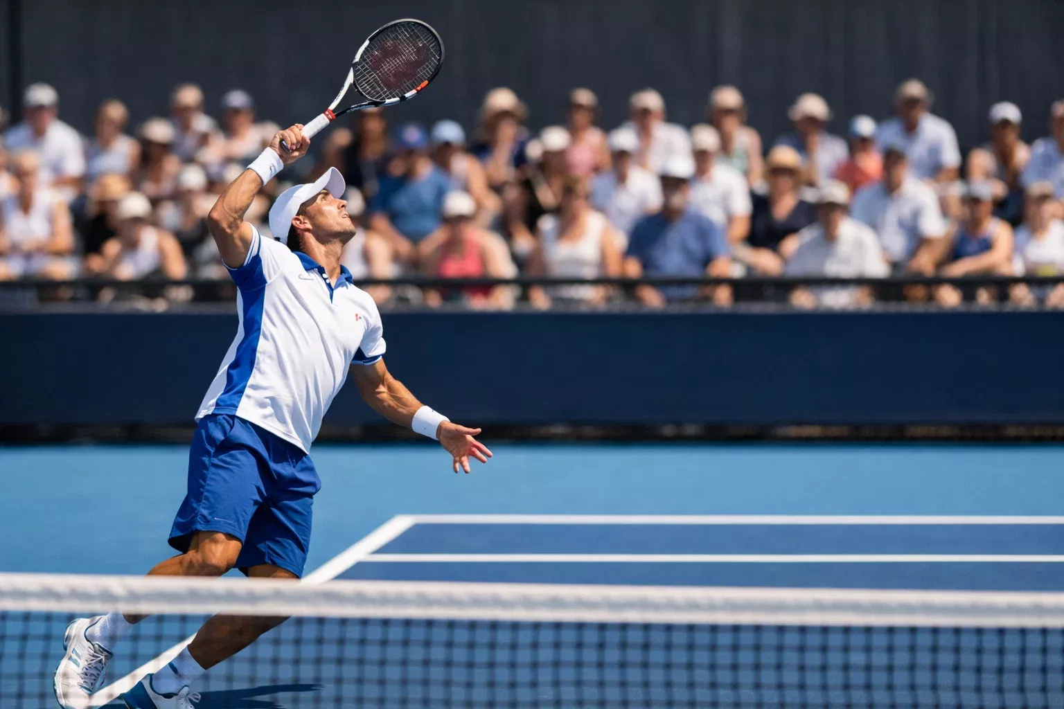 Tennisspieler serviert auf einem Hartplatz bei Tageslicht mit Zuschauern im Hintergrund
