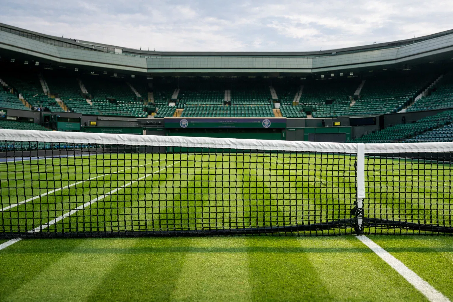 Rasenplatz in Wimbledon mit weissen Linien und dem Centre Court im Hintergrund